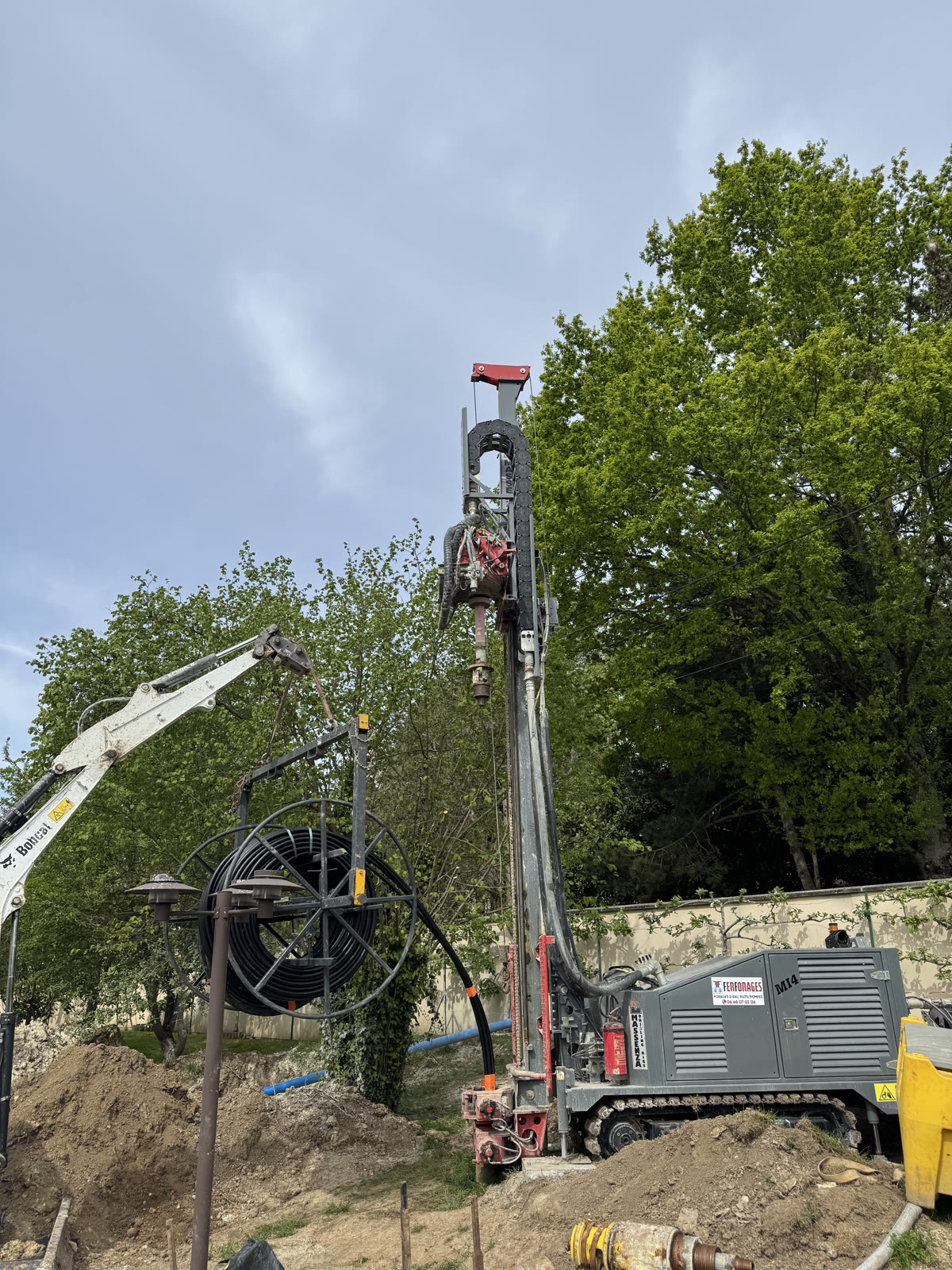 Foreuse et bobine de sonde lors de la pose d'une sonde géothermique verticale.
